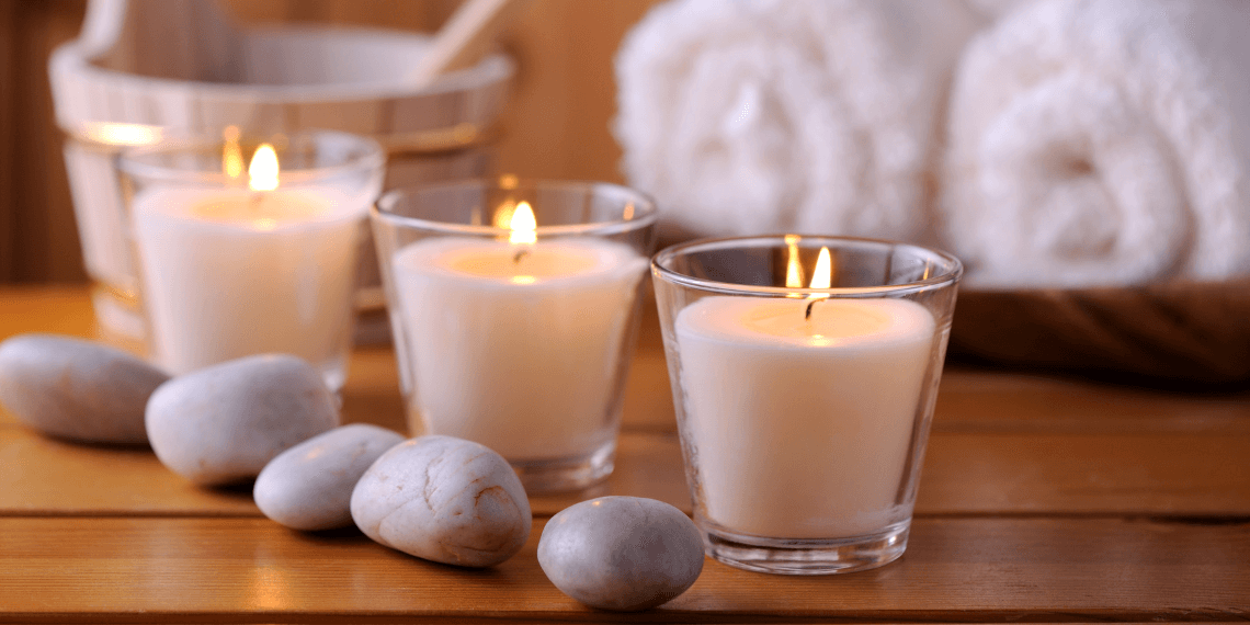 Image depicts a serene spa setting, featuring warmly lit candles and smooth rocks carefully arranged to create a calming ambiance. The gentle glow of the candles casts a soft light, highlighting the natural textures and tranquil atmosphere, ideal for relaxation and meditation.