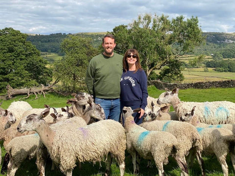 Rob and Lisa Berry standing in the middle of their flock of sheep