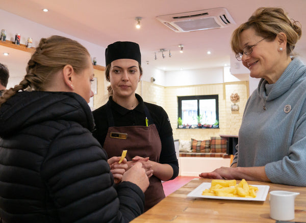 The Real Food Cafe staff tasting freshly cooked chips at the table