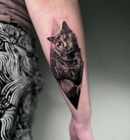 Tattoo of a black cat with a pumpkin