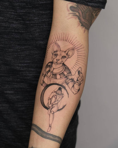 Fine line tattoo of an Egyptian dressed hairless cat manipulating a puppet