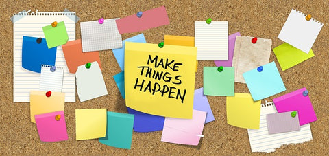 corkboard covered with notes of various colors and sizes. In the center is a large yellow note that has "Make things happen" written on it in black capital letters.