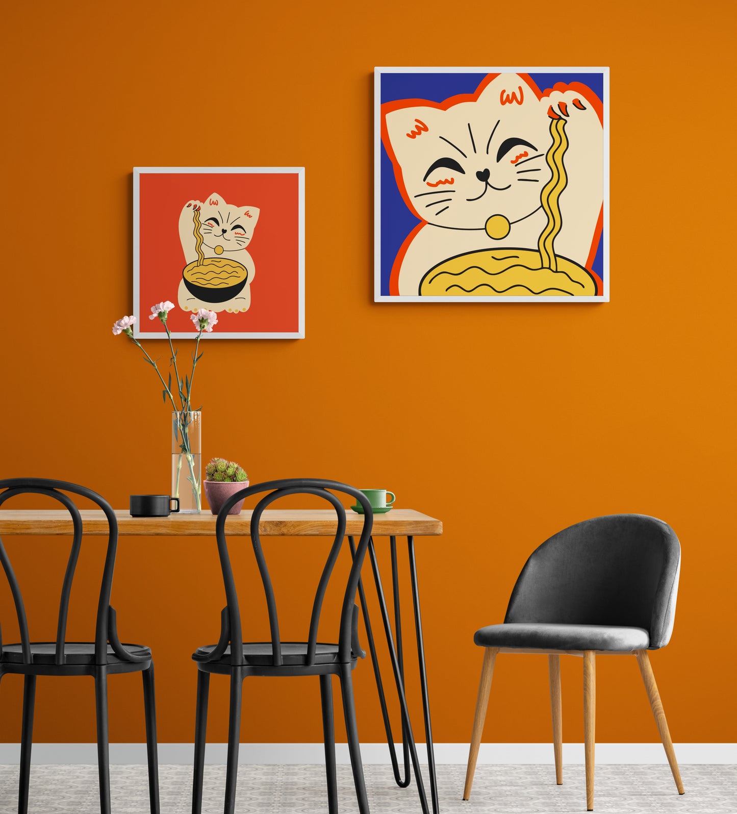 Dans une salle a manger les murs sont orange au centre une table et des chaise au style industrielle. deux tableaux de chat maneki-neko sont accroché au mur