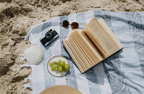 serviette de plage sur le sable avec lunettes de soleil et livre