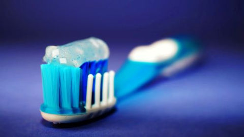 Une brosse à dents est posée à l'horizontale avec du dentifrice dessus