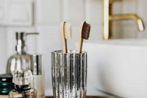 2 brosses à dents sont tenues dans un verre en face du miroir de la salle de bain