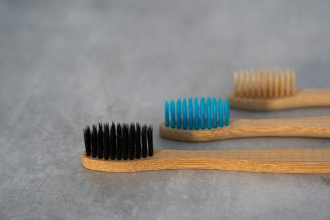 3 brosses à dents en bois avec les poils de couleurs différentes se tiennent côtes à côtes