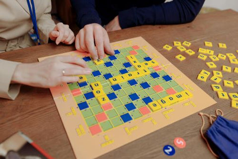Des gens jouent au Scrabble mais on ne sait pas s'ils s'amusent car on ne voit pas leurs visages