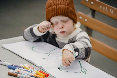 Un enfant est en train de dessiner avec ses feutres