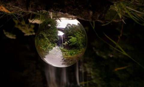 Une goute d'eau suspendue au plafond d'un rocher reflète une cascade entre deux roches