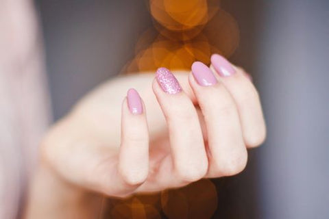Une femme montre ses ongles roses réalisés à l'aide d'un set de manucure personnalisable trans laser
