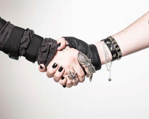 Deux personnes au look gothique se serrent la main et portent des bracelets