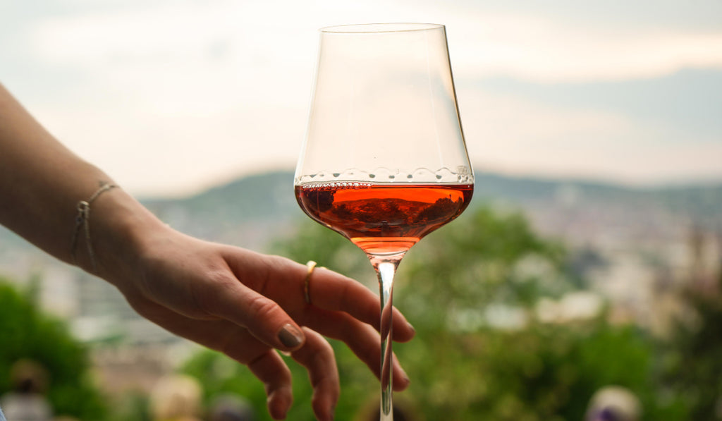 Eine Frau die nach einem Glas Roséwein greift, im Hintergrund Stuttgarts Skyline