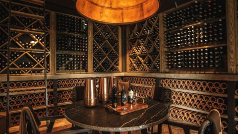 well lit and beautifully designed wooden Wine cellar with table and chairs 