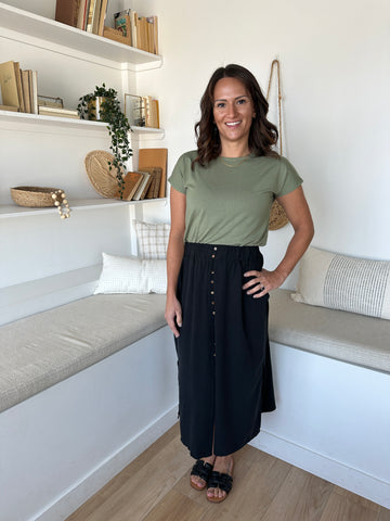 Woman wearing sage green bamboo crewneck t-shirt and black midi length skirt with buttons