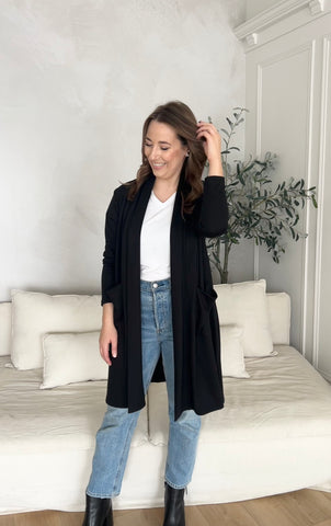 woman wearing black long cardigan with pockets, white bamboo v-neck t shrit and jeans with black boots