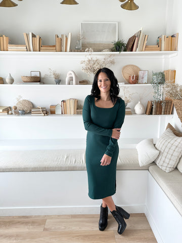 woman wearing long sleeved dark green dress with square neckline and black ankle boots