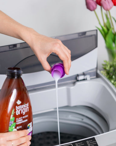 person pouring laundry detergent into washing machine