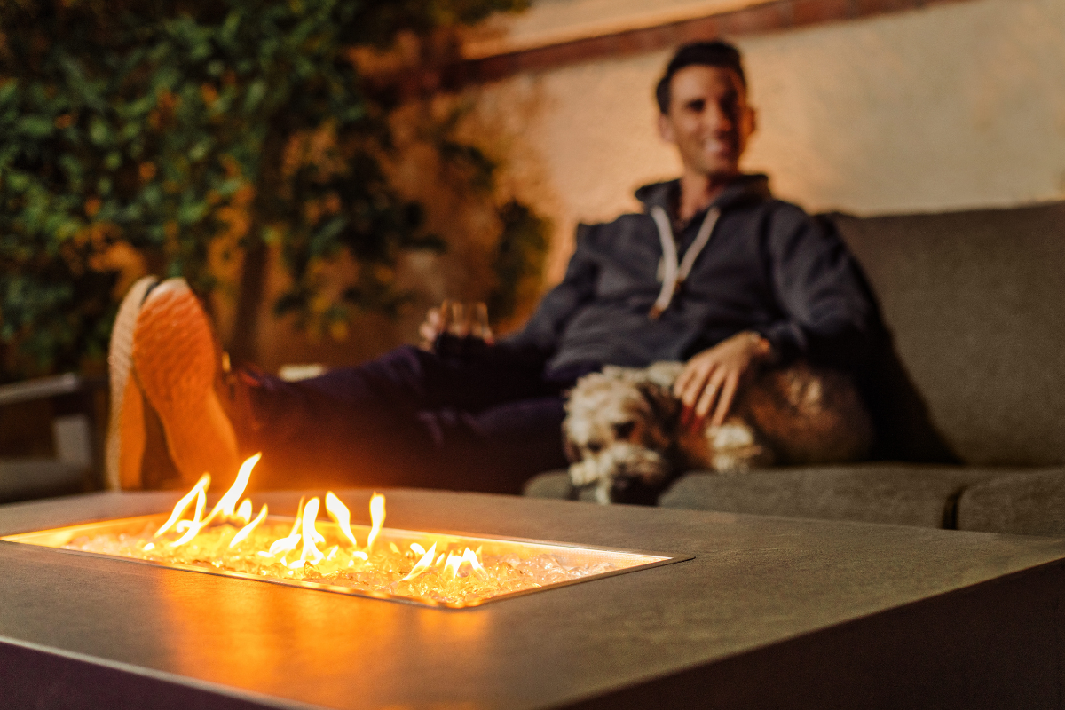 Person Sitting on Comfy Sofa With Dog and Fire Table