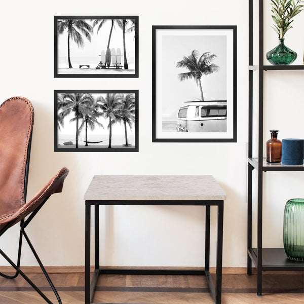 Display of black and white beach art in black timber frames