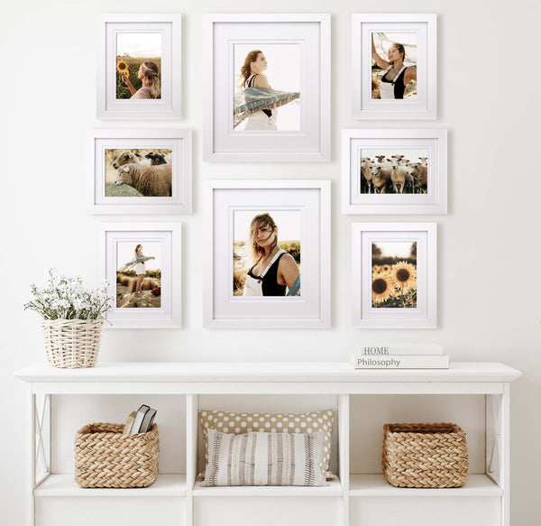 Set of white framed photos in a gallery display on wall