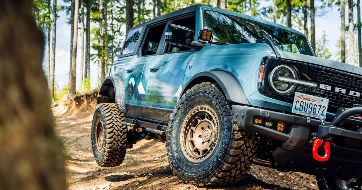 light blue bronco off roading with rear wheel off ground