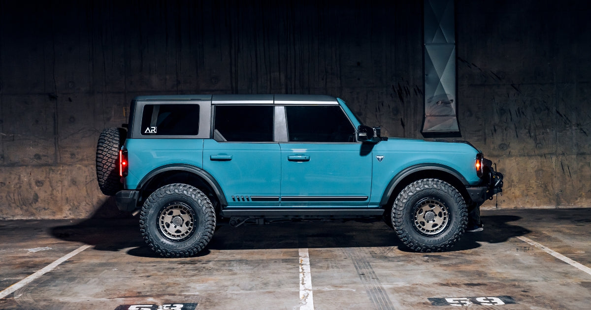 a side view of an accessory ready blue ford bronco in a parking garage