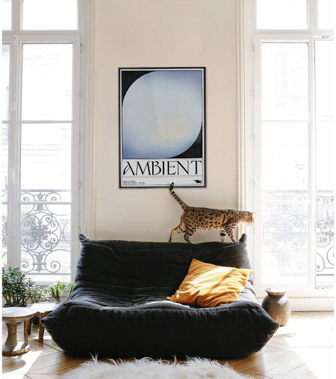 sitting room with a togo sofa, a cat walking on the top of it and a framed blue artwork hung on the wall above it
