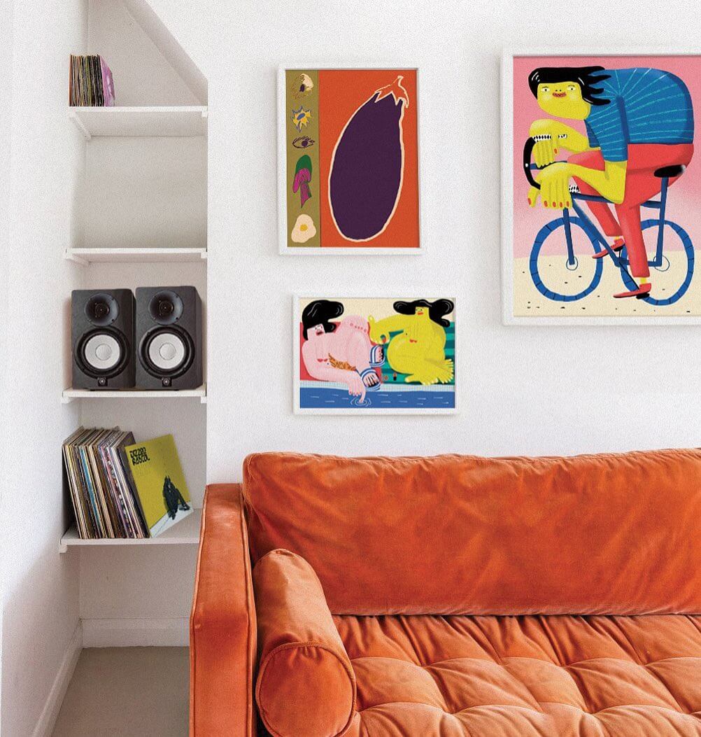 mid century modern living room with a bright orange sofa and a 3 artwork gallery wall hung above it