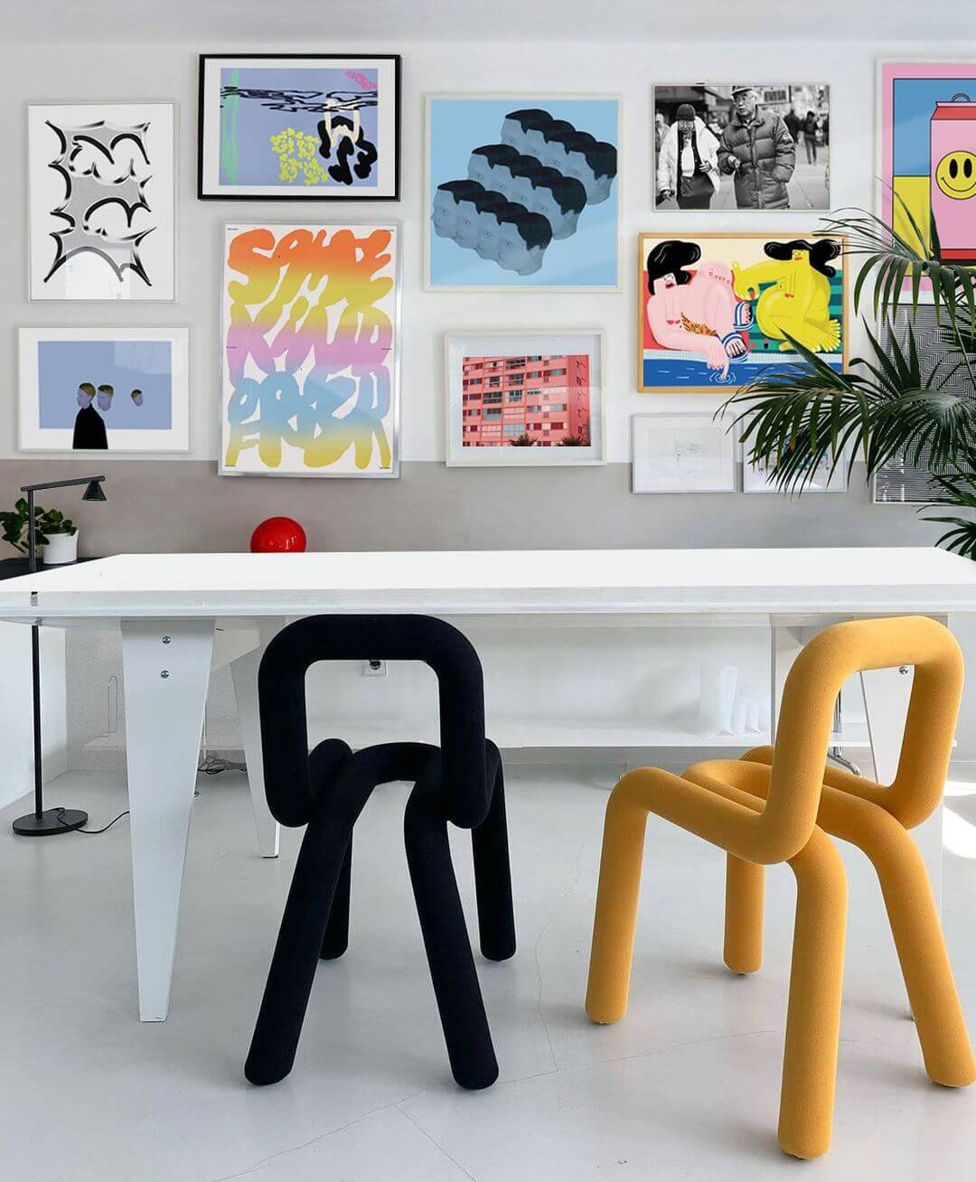 contemporary office with bold coloured chairs and a massive framed gallery wall featuring lots of colourful illustration and graphic design artworks