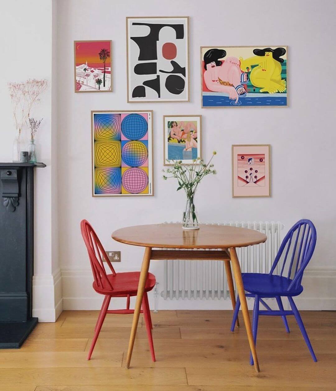 small dinning room with red and blue chairs and a contemporary gallery wall hung above it