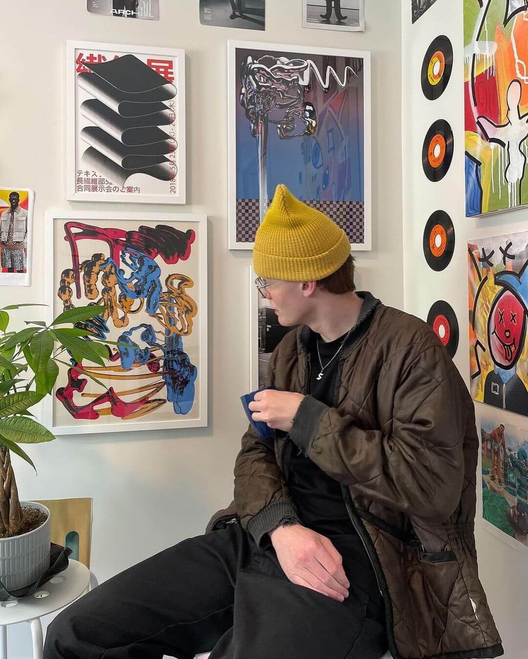 man sitting in his studio looking at framed art works