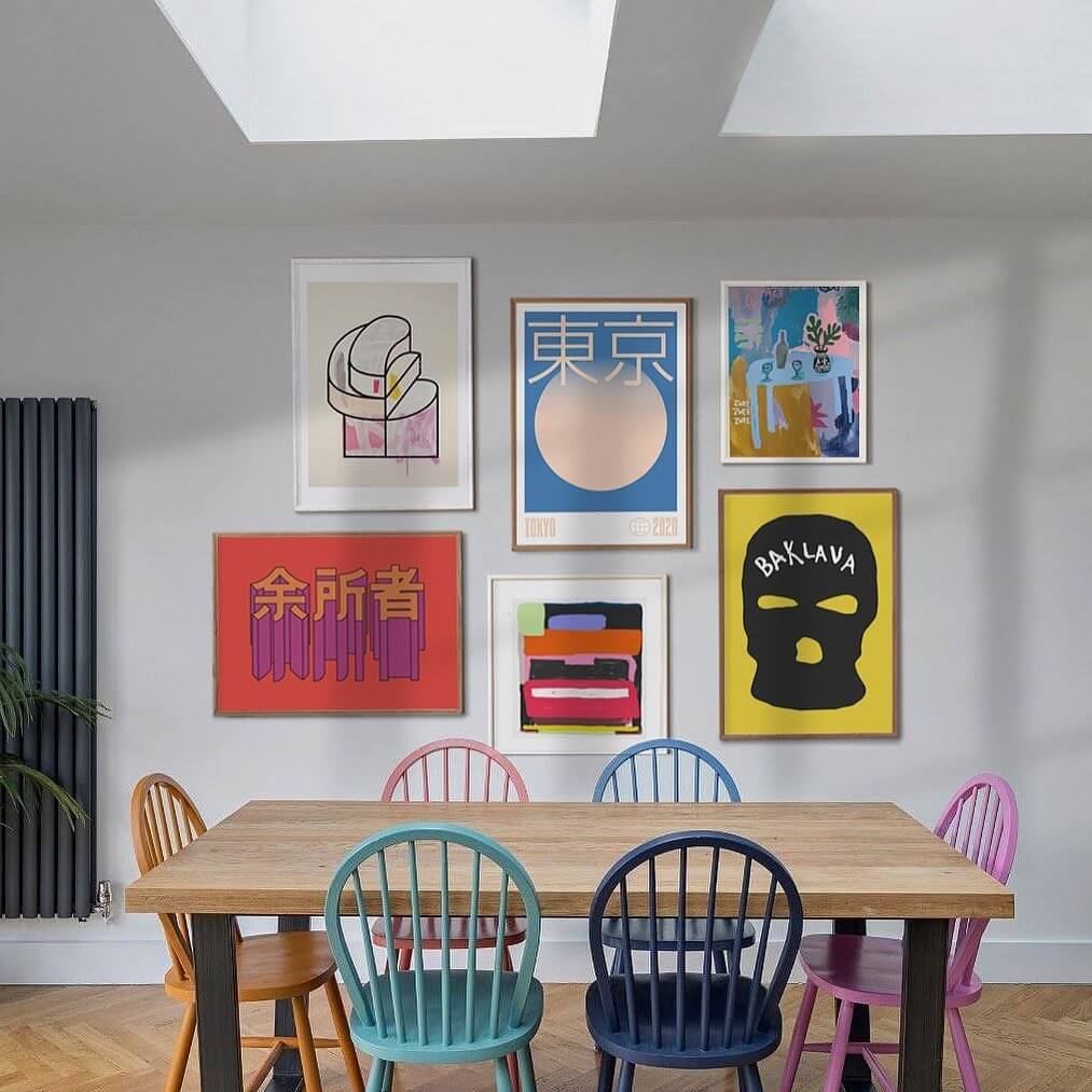 dinning room with coloured chairs and a large gallery wall displaying illustration and painting art prints