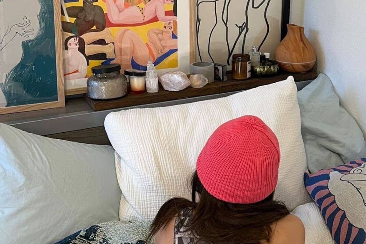 girl lying on the bed staring at framed artwork