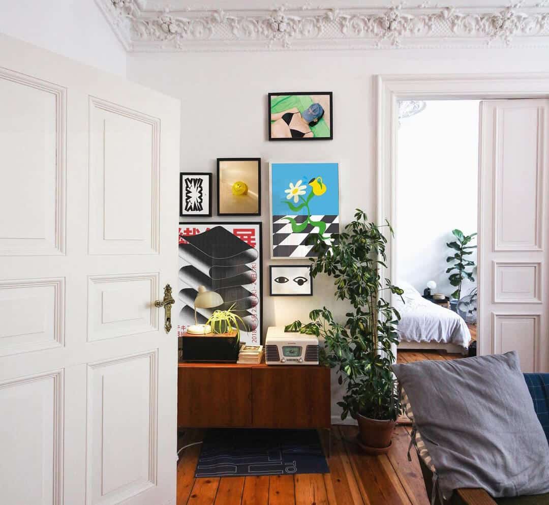 gallery wall displayed in a mid century modern flat with exposed wooden floor, high ceilings and vintage detailing on the ceiling