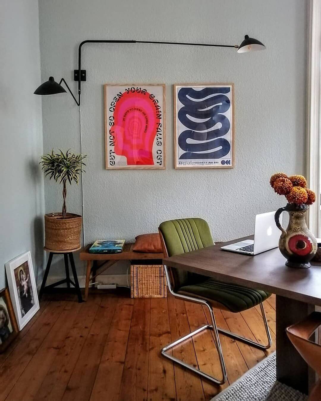mid century modern interior with exposed wood flooring an arc wall lamp, vintage green chair and 2 framed contemporary art prints