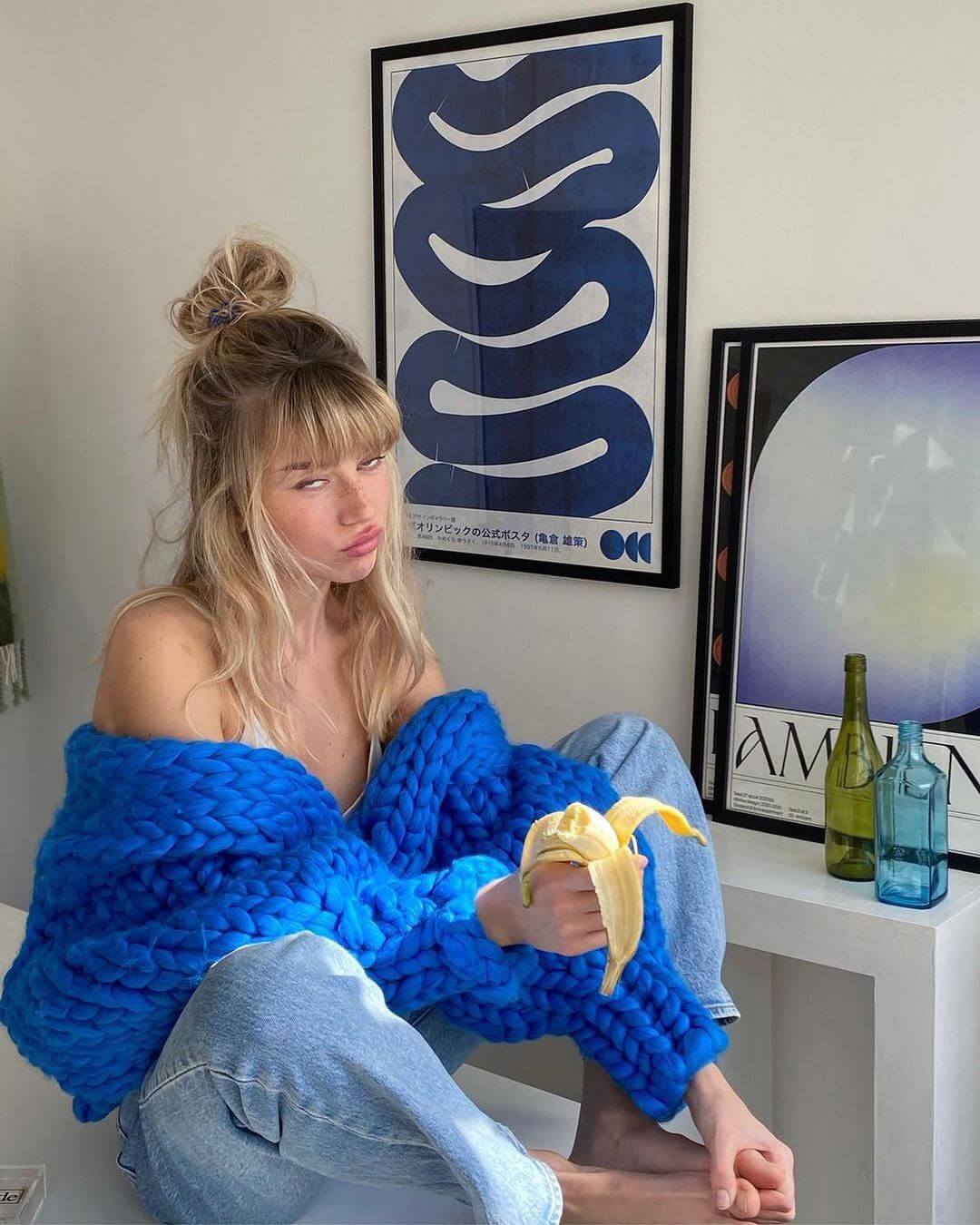 photo of a girl sitting in front of 2 blue framed artworks
