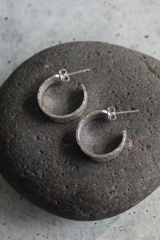 Handmade sterling silver wide hammered hoops on posts, approximately 1/2" in diameter.