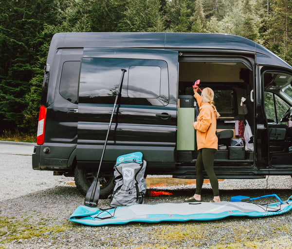 Woman taking items out of car while also inflating her NAUTICAL standup paddleboard