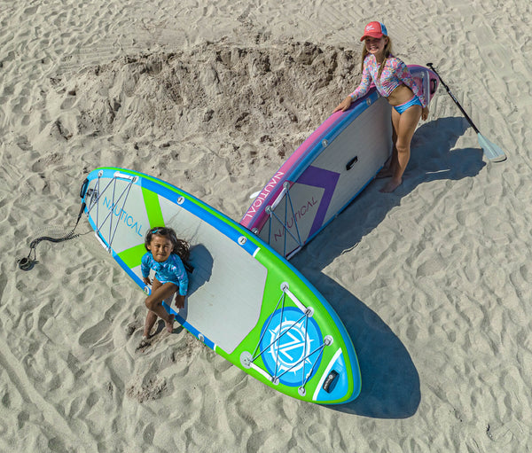 Two young girls posing in front of their NAUTICAL kids standup paddleboards on the beach