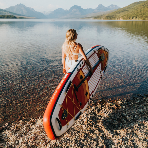 Woman carrying BLACKFIN standup paddle board to the water