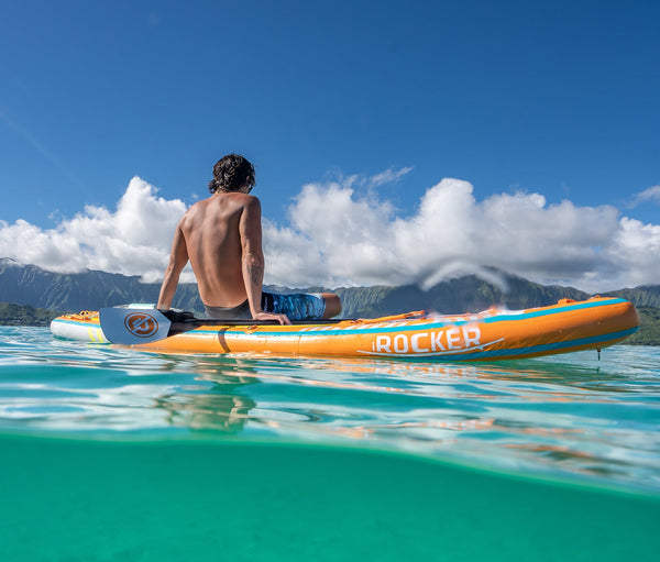 Man sitting on a iROCKER stand up paddle board in the water