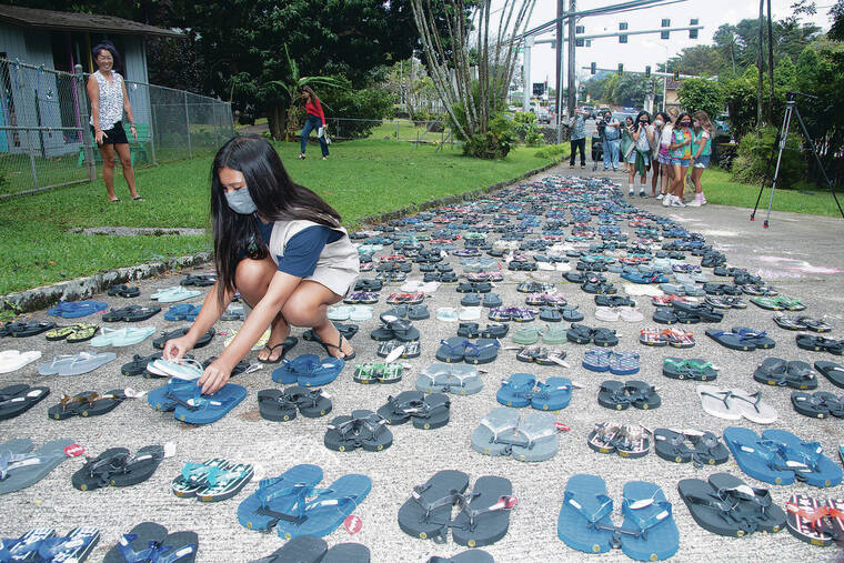 Rylie Ramiro helps her Girl Scout Troop 30 arrange slippers