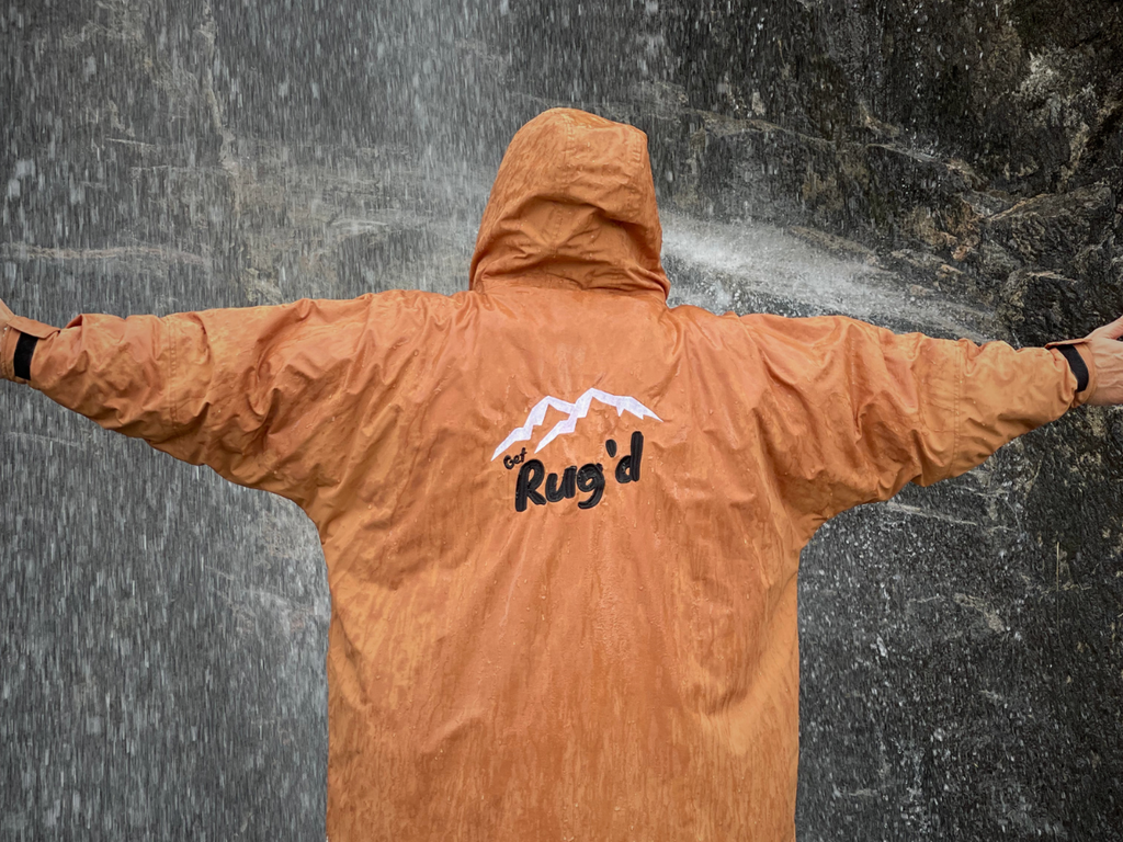 Get Rug'd HydroCloak Ultimate Changing Robe and alternative to Hooded Towel is waterproof. Person standing in front of waterfall wearing outdoor changing robe.