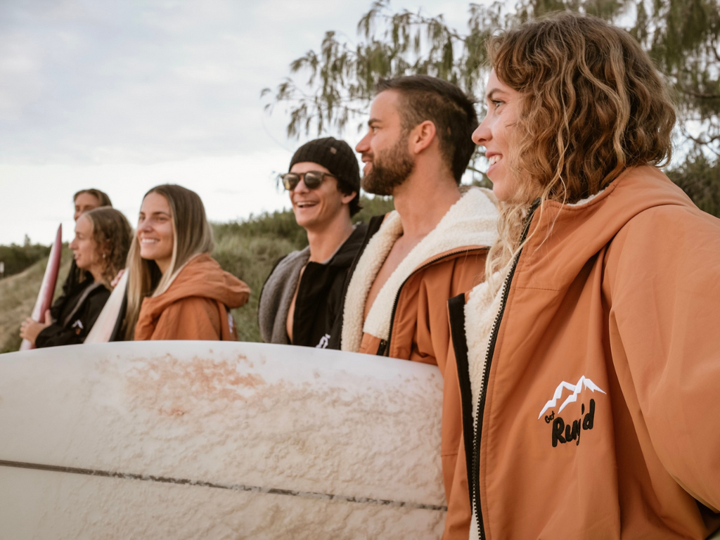 Get Rug'd HydroCloak Changing Robe and Hooded Towel Poncho worn by a group of surfers male and female in front of trees