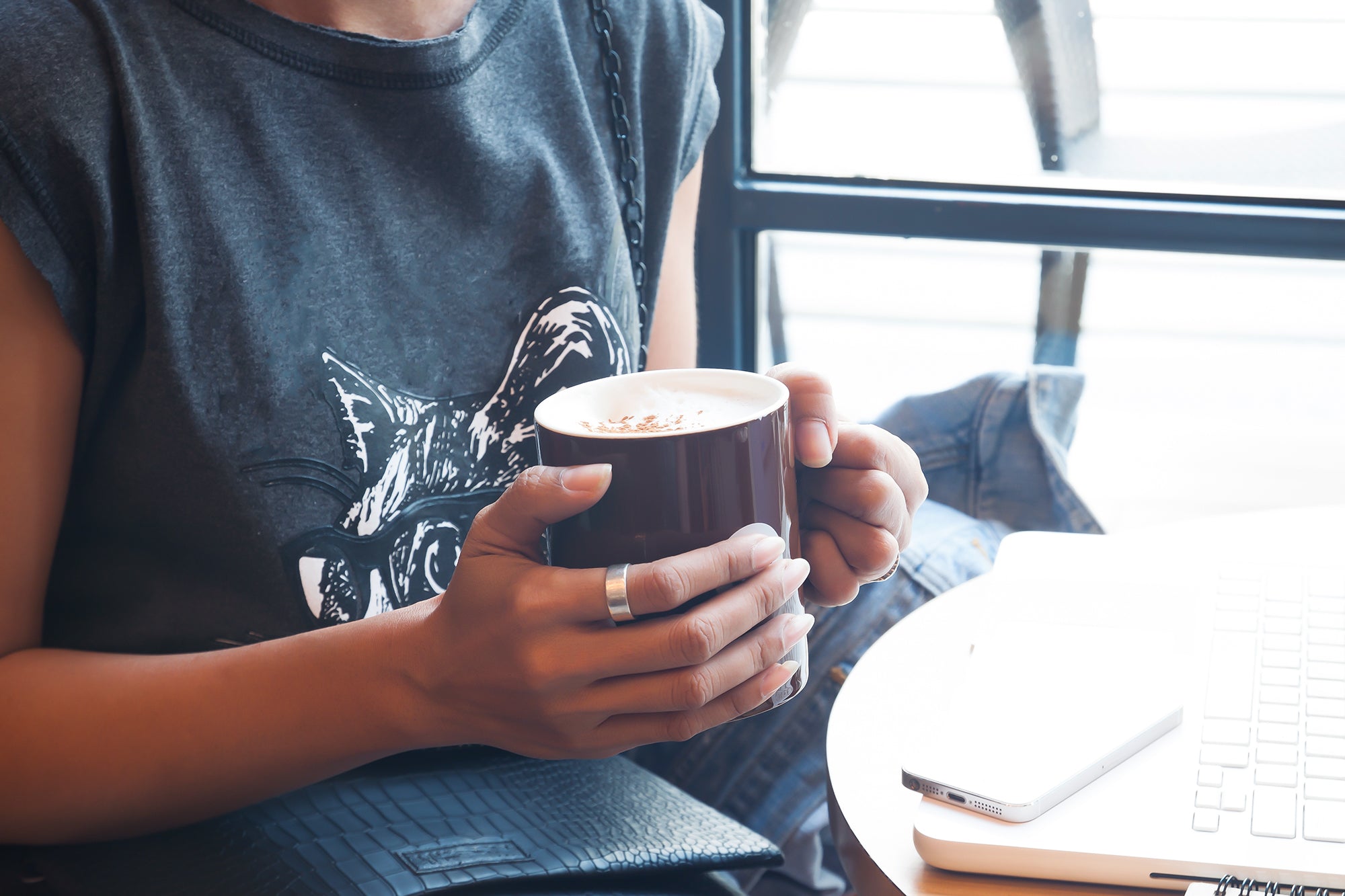 Woman in dark t-shirt holding blue coffee cup in hands