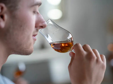 Ein Mann riecht in sein Whisky Glas