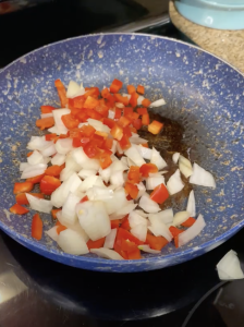 To a pan add onions, bell pepper and saute in oil at medium high heat for about five minutes.