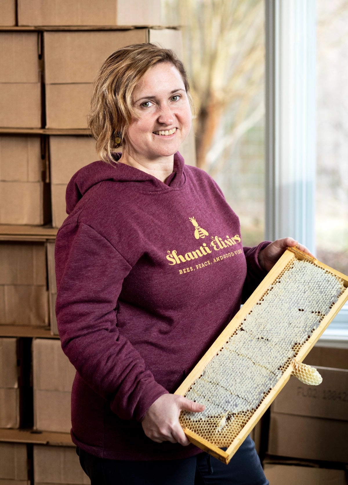 Shanti Volpe creator of Shanti Elixirs Jun probiotic drink holding capped honey frame