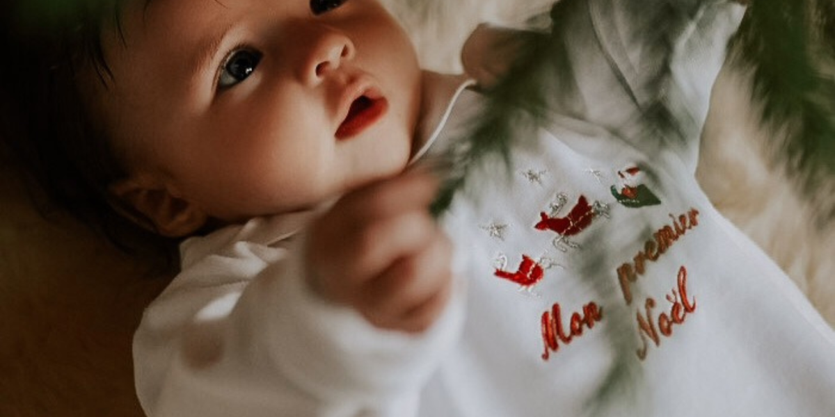 Photo d'un bébé portant un pyjama en velours blanc brodé "Mon premier Noël"